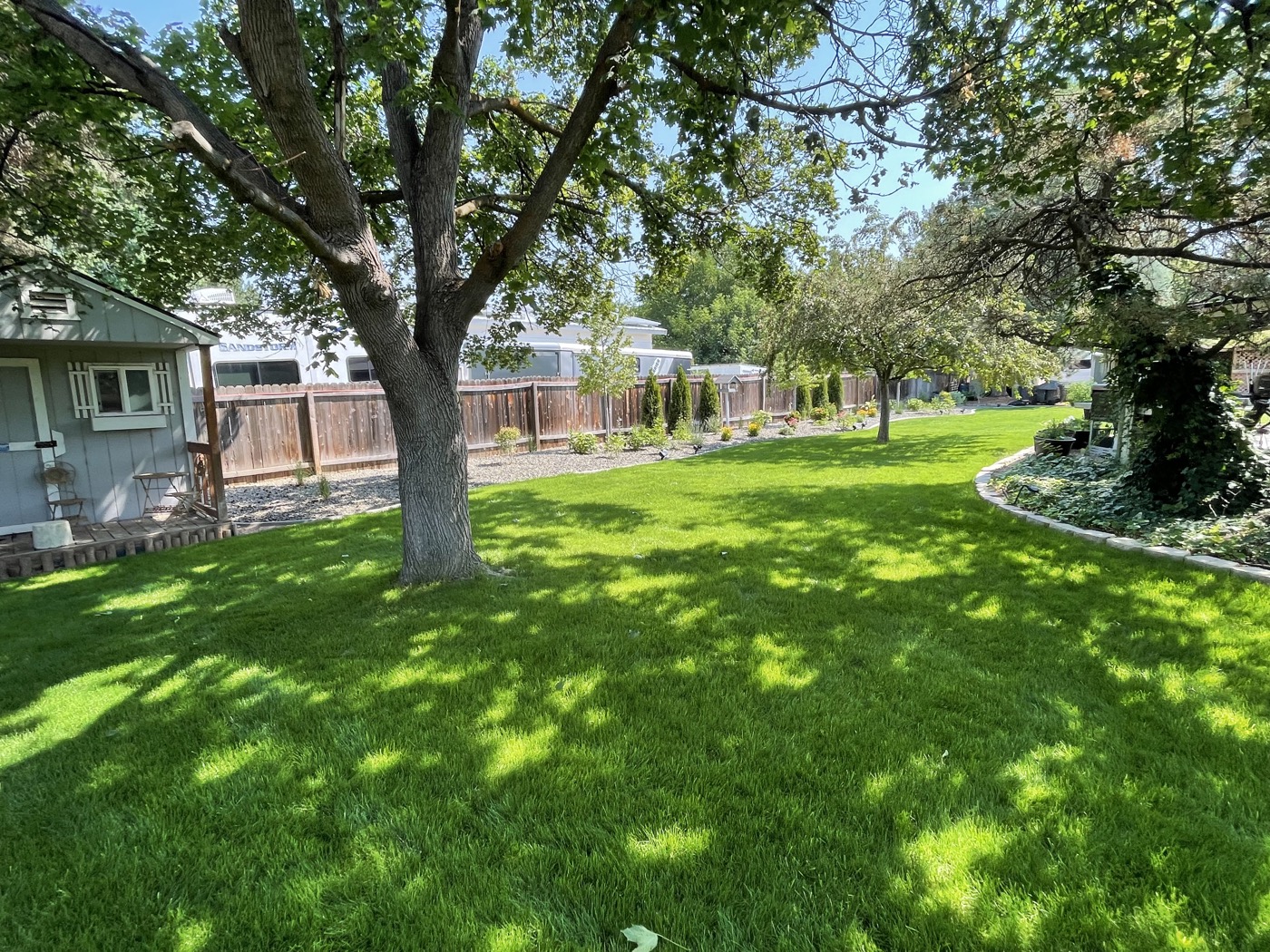 Lush backyard with mature shade trees and manicured lawn